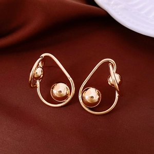 Gros plan détaillé de boucles d'oreilles boules torsadées dorées sur soie rouge foncé