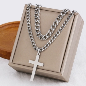 Detail of silver stainless steel cross pendant on curb chain over a gift box