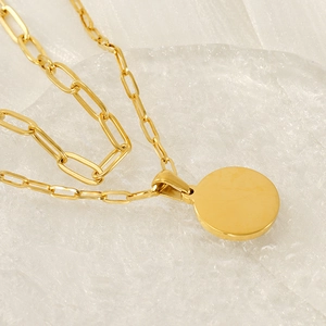 Collier chaîne trombone dorée avec pendentif rond minimaliste sur support verre