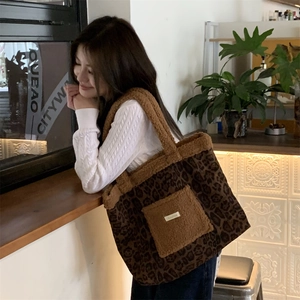 Chic leopard print tote bag with brown plush faux fur trim carried by model in cafe