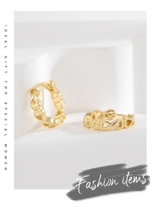Detail view of gold hollow heart hoop earrings on a minimalist geometric display stand
