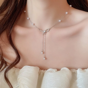 Detail showing elegant silver bow pendant with shimmering pearls and zircon inlay