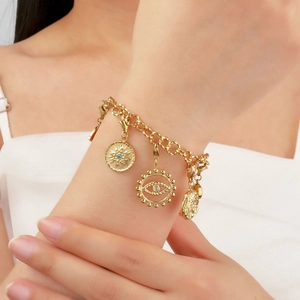 Gold evil eye bracelet with star and coin charms featuring blue cubic zirconia