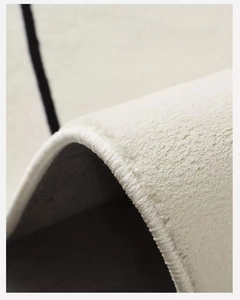 Macro shot of faux cashmere rug edge showing soft off-white pile and premium stitching