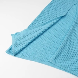 Gros plan détaillé du tissu en maille crochet bleue montrant la texture ajourée et l'ourlet