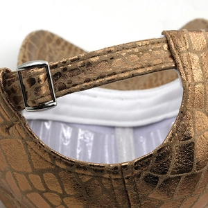 Detailed macro view of crocodile embossed leather and silver adjustable buckle on baseball cap