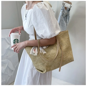 Detail of hand-woven straw tote bag with delicate white lace and rose floral embroidery