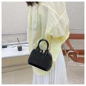 Detail of black shell bag featuring 3D dot texture and golden chain strap for summer