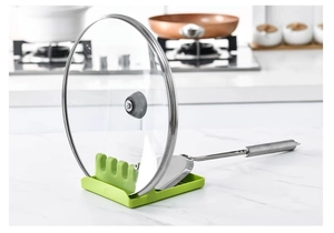 Dettaglio macro dell'organizzatore da cucina verde per coperchi e poggia spatola sul ripiano