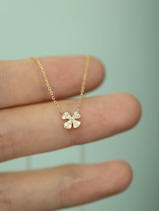 Macro shot of 14k gold clover pendant with pave-set zircons on a dainty chain