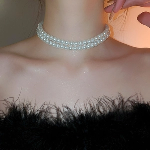 Détail du collier de perles double épaisseur avec nœud élégant et pendentif pompon