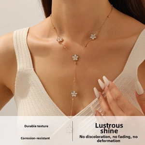 Détail du collier chaîne dorée en Y avec breloques fleurs blanches et perles nacrées