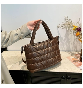 Detail of chocolate brown quilted down tote bag with glossy nylon finish and shoulder strap
