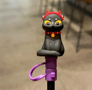 Detail eines 10mm Silikon-Strohhalmdeckels als schwarze Katze mit lila Basis und rotem Band