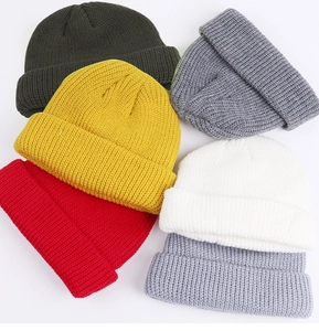 Detailed view of colorful knitted beanie caps in yellow, red, and grey shades