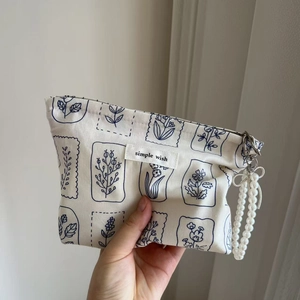 Detail of floral print canvas pouch with pearl strap and simple wish woven label