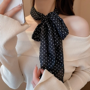 Close-up of black and white polka dot silk scarf worn with an off-shoulder sweater