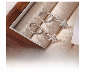 Macro shot of silver textured starfish drop earrings in a luxury wooden jewelry gift box