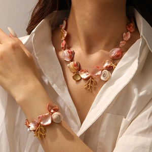 Close-up of ocean-style necklace and bracelet set with shell slices and coral charms