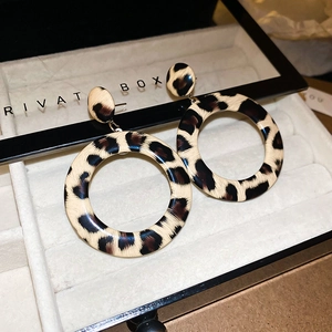 Close-up of leopard print resin hoop earrings on a beige velvet jewelry tray