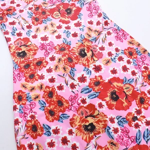 Close-up of bright pink floral print dress showing vibrant red and blue flower details