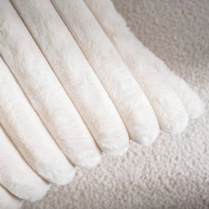 Macro detail of beige faux rabbit fur pillow with soft striped texture and plush surface