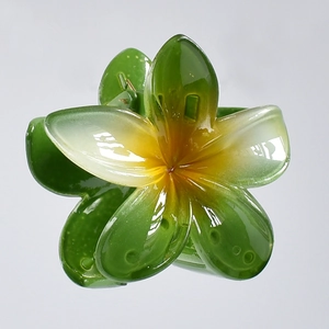 Detail of a 7cm green plumeria flower hair claw clip with glossy acetate finish