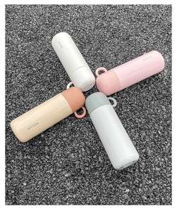 Top view of four colorful stainless steel vacuum flasks with handles on stone ground
