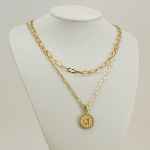 Detail of double-layer gold necklace with paperclip chain and letter J coin pendant