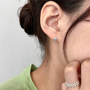 Elegant 925 silver heart stud earrings with blue zircon on a female model