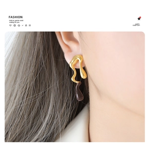 Detail of liquid melting-style drip glaze earrings in gold and brown on model
