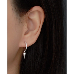 Detailed close-up of a silver cone earring with pavé diamonds on a model side profile