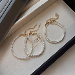 Detail of vintage gold pearl bracelet set with adjustable lobster clasp on beige fabric