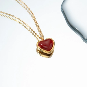 Close-up of 18k gold-plated chain featuring a polished red heart pendant on white background