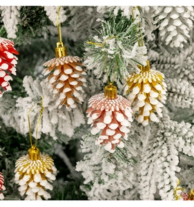 Détail de suspensions pommes de pin colorées enneigées sur une branche de sapin de Noël blanc