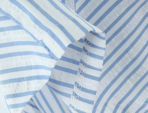 Detailed close-up of blue and white striped seersucker fabric showing fine stitching