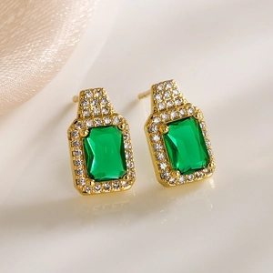 Macro detail of gold square stud earrings with green zircon and clear stones