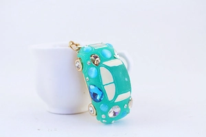 Close-up of a teal car keychain with colorful rhinestones on a white background
