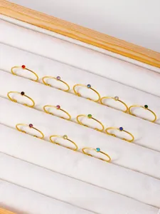 Macro view of minimalist gold rings with colorful round zircon stones in a velvet box