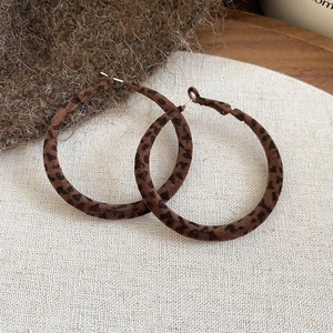 Gros plan de boucles d'oreilles créoles léopard avec texture en velours marron et noir