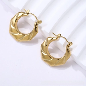 Detail of 18K gold titanium earrings with geometric twist design on a white display