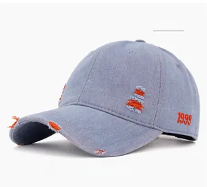Close-up of distressed light blue denim baseball cap with orange 1999 embroidery