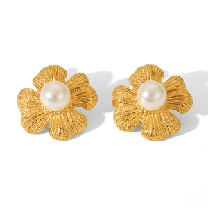 Nahaufnahme goldener Blumenohrringe mit weißen Perlen und feiner Blütenstruktur