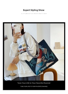 Detail of navy canvas tote bag with colorful embroidery and striped woven handles