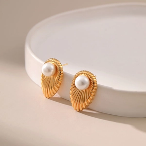Dettaglio macro degli orecchini a conchiglia placcati oro 18K con perle su vassoio ceramico