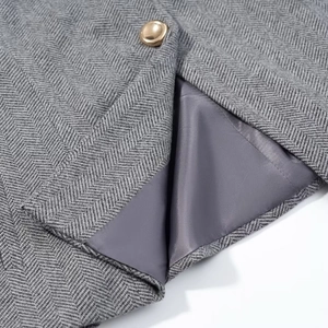 Détail du tissu gris à chevrons avec bouton doré et doublure en soie lisse