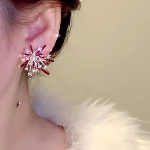 Detailed close-up of firework-shaped stud earrings with red gems and central pearl