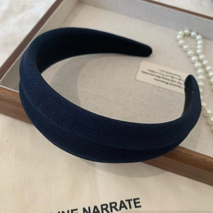 Detail of dark blue ribbed fabric headband with sponge padding on a wooden display