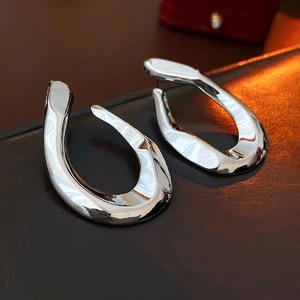 Macro detail of silver twisted U-shaped stud earrings with polished mirror finish