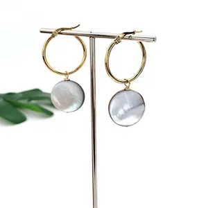 Macro view of 25mm gold stainless steel hoop earrings with grey natural shell pendants